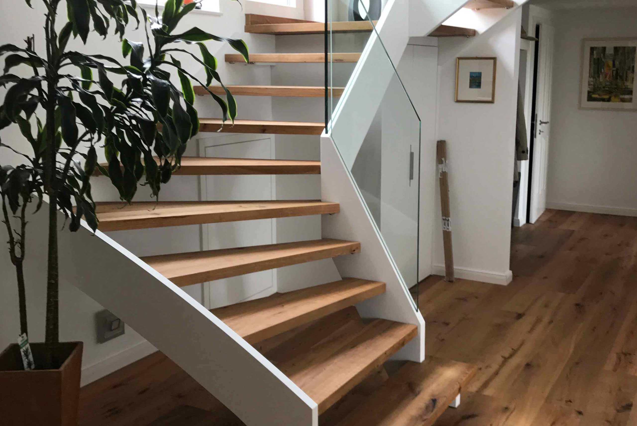 Moderne Treppe mit Hellen Holstiegen und weiß gestrichener Verkleidung sowie Glasgeländer